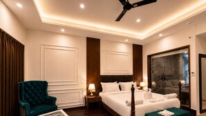 A hotel room with a bed, a chair, a nightstand, a table, and a ceiling fan.