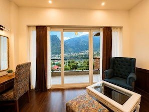 Una habitación con un amplio ventanal corredero, una silla, un sofá y una mesita.