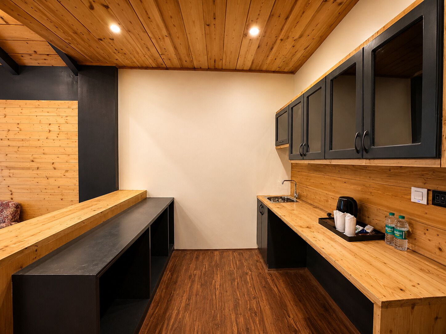 Una cocina compacta con encimeras de madera, un lavamanos y armarios negros.