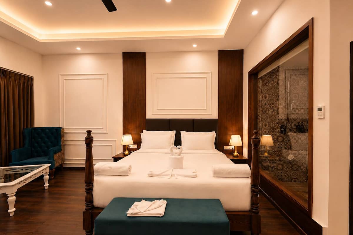 A hotel room with a large bed, two bedside tables, a chair, a bench, and a large framed artwork on the wall.