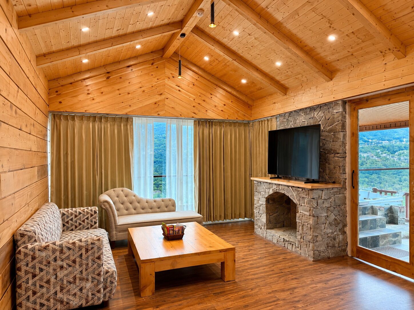 A wooden interior with a stone fireplace, a sofa, a chair, and a television.
