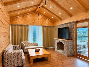Un interior de madera con chimenea de piedra, un sofá, un sillón y un televisor.