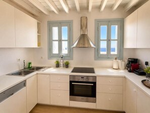 A modern kitchen with white cabinets, a stainless steel range hood, a double sink, and a built-in oven. - Villa Delos Mystique Mykonos (Mykonos)