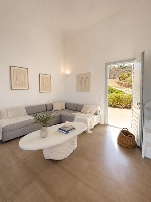 Ein modernes Wohnzimmer mit einem grauen Ecksofa, einem weißen Couchtisch und gerahmten Kunstwerken an den Wänden.
