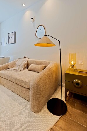 A modern living room with a sofa, a floor lamp, a side table with a lamp, and a wall-mounted light fixture. - Saristays Valencia Luxe Style (València)