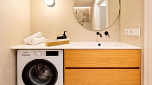 Un bagno moderno con lavatrice, lavandino, specchio e porta asciugamani.