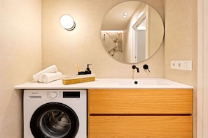 A modern bathroom with a washing machine, a sink, a mirror, and a towel rack. - Saristays Valencia Luxe Style (València)