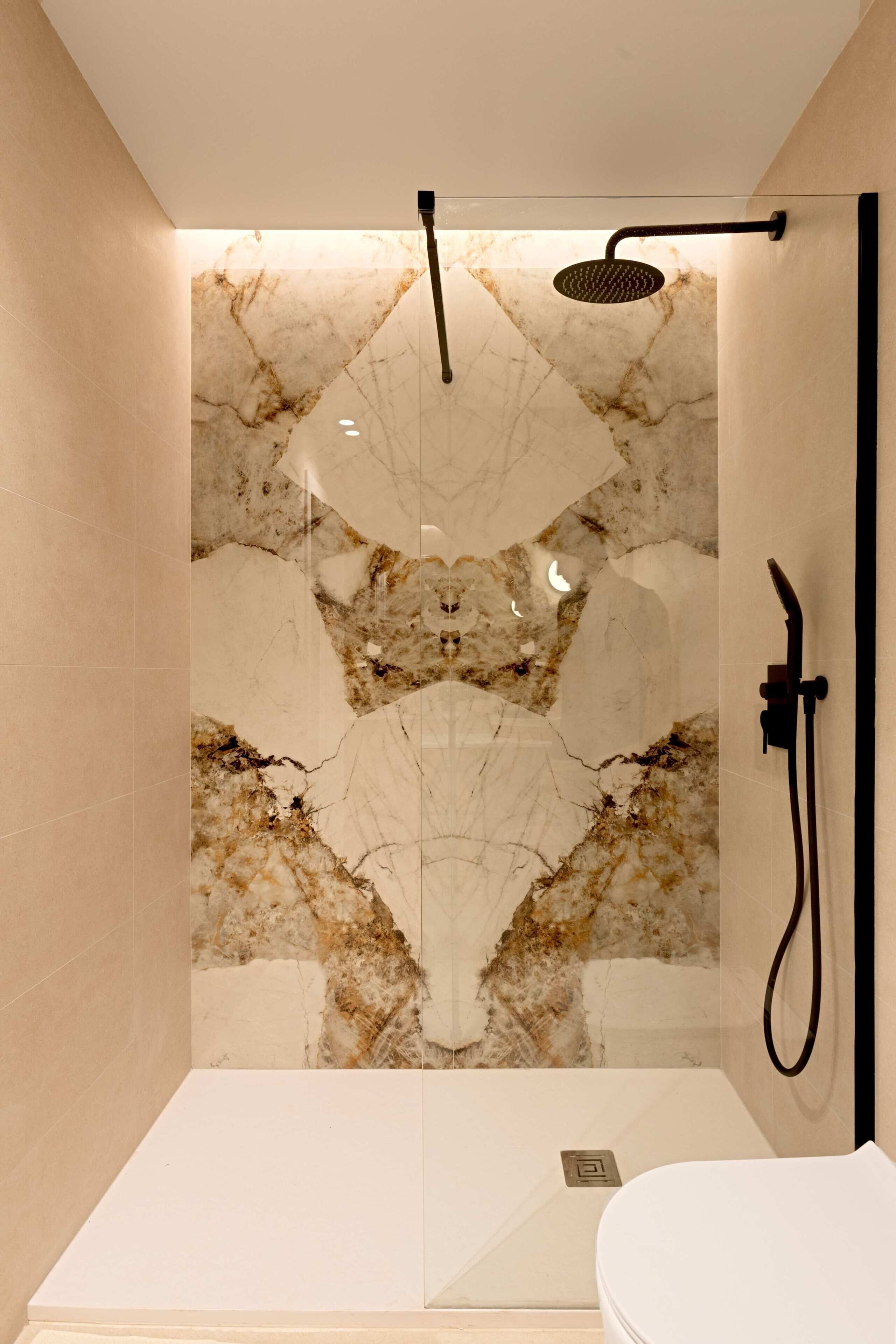 A modern bathroom with a marble wall, a shower area, and a toilet.