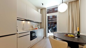 Una cucina moderna con mobili bianchi, un forno nero e una zona pranzo con un tavolo rotondo e sedie.