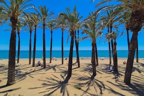 Une plage bordée de palmiers où des gens se prélassent au soleil.