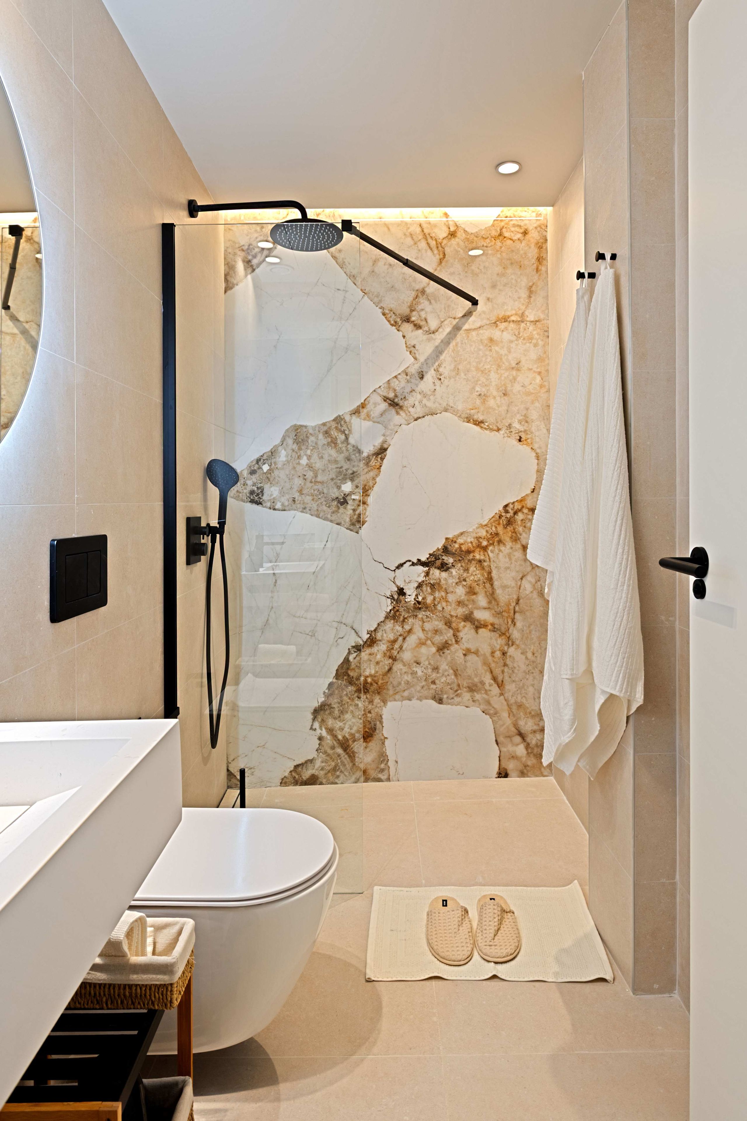 Un baño con bañera, ducha, pared de mármol y toallero.
