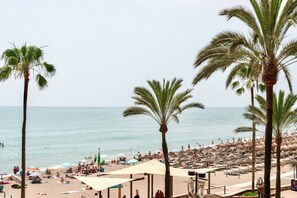 Ein Strand mit Palmen, Sonnenschirmen und Menschen.