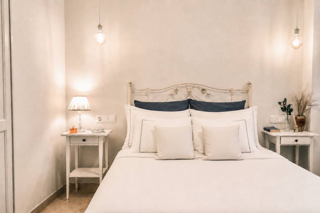 A neatly arranged bedroom with a bed, bedside tables, and a lamp.