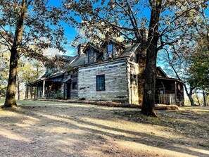 A rustic wooden cabin with a porch, surrounded by trees.