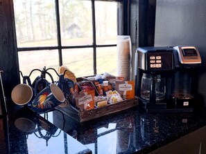 Un comptoir de cuisine avec une machine à café, une cafetière et un plateau rempli d’aliments pour le petit-déjeuner.