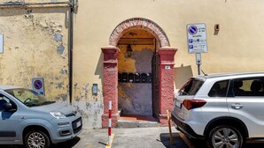 A parking area with a no parking sign, a building entrance with a red archway, and a vehicle parked inside.