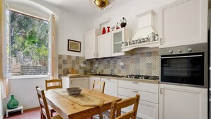 A kitchen with white cabinets, a wooden table, and a view of the outdoors through a window.