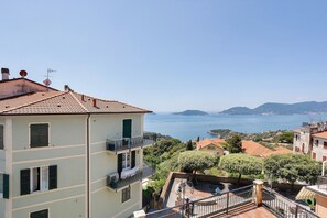 Un edificio de varios pisos con balcones, vistas al mar y vegetación circundante.