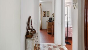 A hallway leading to a bedroom with a bed, a dresser, and a mirror.