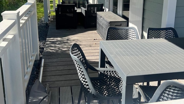 A covered patio with outdoor furniture, a white fence, and a view of neighboring houses.
