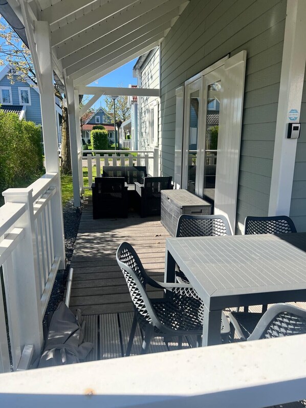 A covered patio with outdoor furniture, a white fence, and a view of neighboring houses.