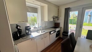 A modern kitchen with a window, built-in cabinets, a sink, and a dining area with a table and chairs.
