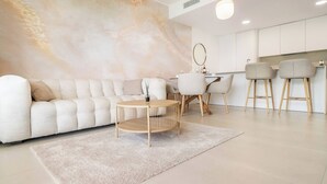 Una sala moderna con un sofá, una mesa redonda de centro y un comedor con sillas.