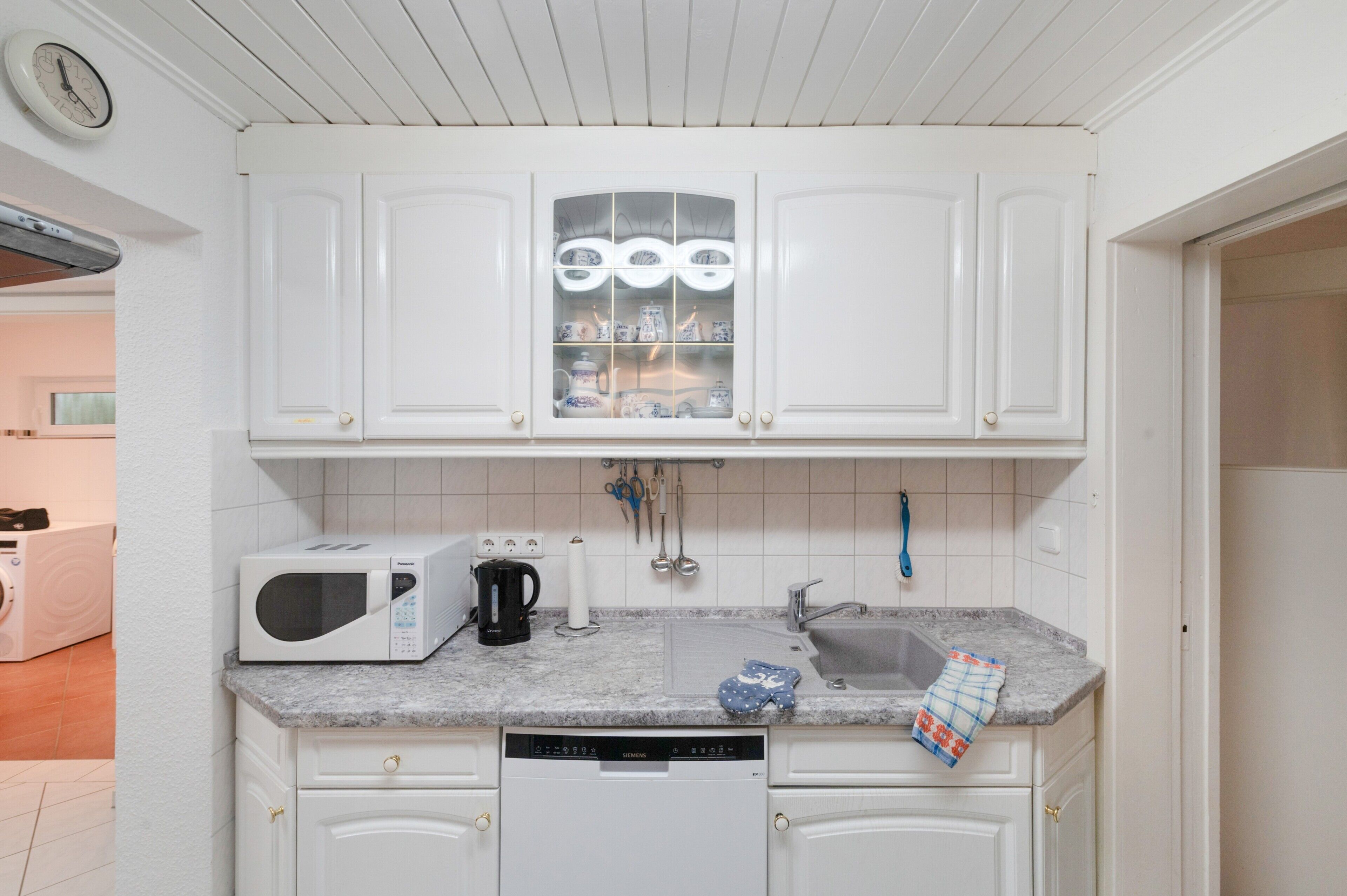 A kitchen with white cabinets, a microwave, a coffee maker, and a Siemens dishwasher.