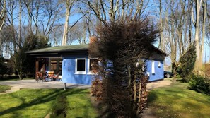 A blue building with a patio area, a small table, and chairs. - Holiday Home for 6 Guests in Graal-Müritz (Baltic Sea Spa) (Graal-Müritz)