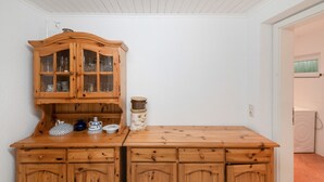 A wooden cabinet with glass doors, a small table with a ceramic jug, and a wall-mounted light fixture. - Holiday Home for 6 Guests in Graal-Müritz (Baltic Sea Spa) (Graal-Müritz)