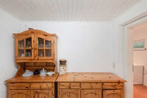A wooden cabinet with glass doors, a small table with a ceramic jug, and a wall-mounted light fixture. - Holiday Home for 6 Guests in Graal-Müritz (Baltic Sea Spa) (Graal-Müritz)
