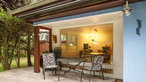 An outdoor patio with a table and chairs, a wooden door, and a view of the interior. - Holiday Home for 6 Guests in Graal-Müritz (Baltic Sea Spa) (Graal-Müritz)