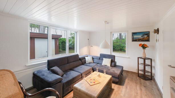A modern living room with a sectional sofa, a wooden coffee table, and a small side table with a vase. - Holiday Home for 6 Guests in Graal-Müritz (Baltic Sea Spa) (Graal-Müritz)