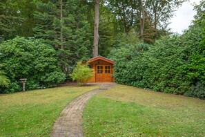 A wooden cabin with a brick pathway leading to it, surrounded by dense greenery. - Holiday Home for 6 Guests in Graal-Müritz (Baltic Sea Spa) (Graal-Müritz)