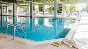 A swimming pool with clear blue water, a metal ladder, and lounge chairs under a patterned ceiling. - "Panorama 86" Indoor Pool, Sauna & Separate Bedroom, Near Lake Constance and the Mountains (Scheidegg)