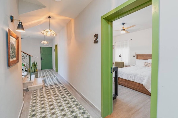 Un pasillo con piso a cuadros, una escalera y una puerta con el número 2.