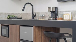Eine moderne Küche mit Holzausstattung, einem Backofen, einer Kaffeemaschine und einem Barhocker.
