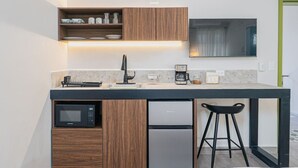 Eine kleine Küchenzeile mit Mikrowelle, Kaffeemaschine und Spüle.