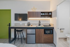 A compact kitchen with a built-in microwave, a coffee maker, and a small refrigerator. - Loft junto al metro | Directo al Estadio BBVA (Monterrey)