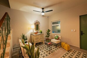 A room with a checkered floor, a ceiling fan, a dresser, a chair with a watermelon cushion, a potted plant, and a suitcase. - Loft junto al metro | Directo al Estadio BBVA (Monterrey)