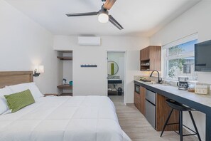 A hotel room with a bed, a kitchenette, a ceiling fan, and a view of the outdoors. - Mitras Centro | Metro directo al Estadio BBVA (Monterrey)