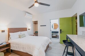 Une chambre à coucher avec un lit, une table de chevet, une commode et un ventilateur de plafond.