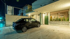 A modern house with a car parked in the driveway, a gated entrance, and a balcony.