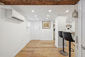 Un corridoio con pareti bianche, pavimento in legno, soffitto con travi a vista e illuminazione a incasso.
