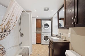 A compact bathroom with a shower, a sink, a toilet, and a built-in washer and dryer. - Modern Suite Minutes from Halifax Waterfront (Halifax)