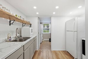 Una cucina moderna con mobili bianchi, un piano di lavoro in marmo, forno integrato e frigorifero.