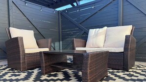 A patio with wicker furniture, a glass table, and a patterned rug. - Coronado Historic Casita · King Bed · Private Yard · Phoenix (Phoenix)