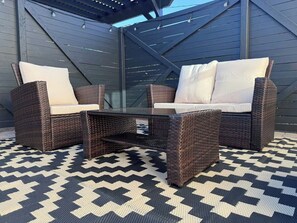 A patio with wicker furniture, a glass table, and a patterned rug. - Coronado Historic Casita · King Bed · Private Yard · Phoenix (Phoenix)