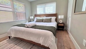 A bedroom with a large bed, two bedside tables, a nightstand, and a mirror. - Coronado Historic Casita · King Bed · Private Yard · Phoenix (Phoenix)