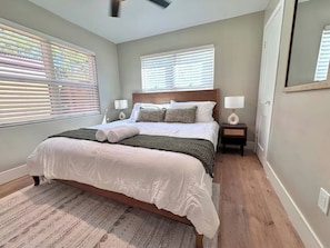 A bedroom with a large bed, two bedside tables, a nightstand, and a mirror. - Coronado Historic Casita · King Bed · Private Yard · Phoenix (Phoenix)